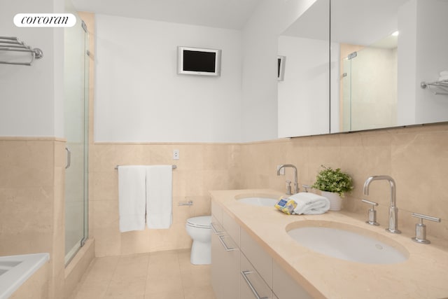 bathroom featuring tile walls, tile patterned flooring, vanity, toilet, and a shower with door