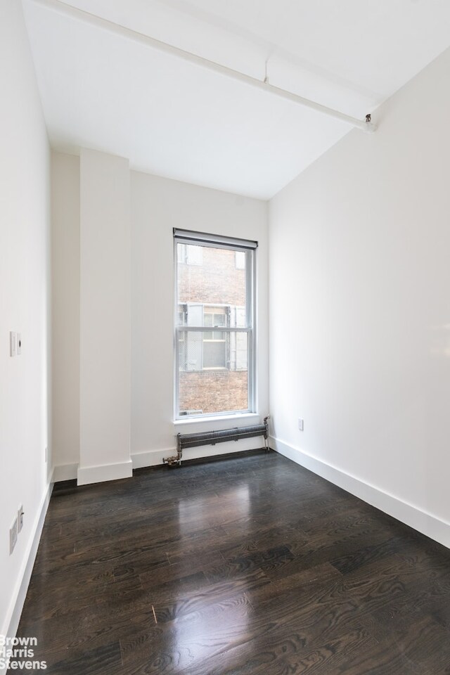 unfurnished living room featuring radiator and dark hardwood / wood-style floors