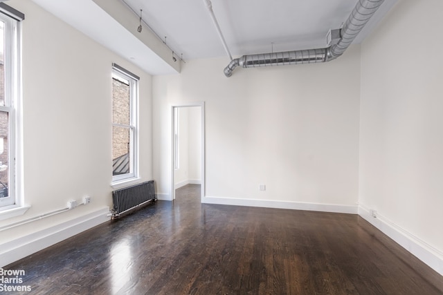 empty room with dark hardwood / wood-style flooring and radiator