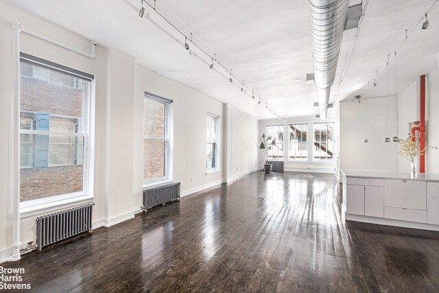 empty room with dark hardwood / wood-style flooring and radiator