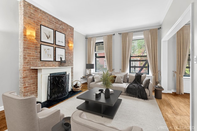 living area with a fireplace, wood finished floors, baseboards, and ornamental molding