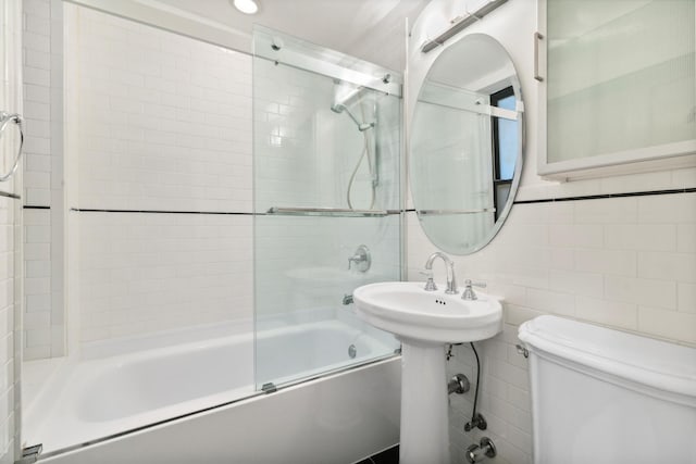 bathroom featuring combined bath / shower with glass door, decorative backsplash, toilet, and tile walls