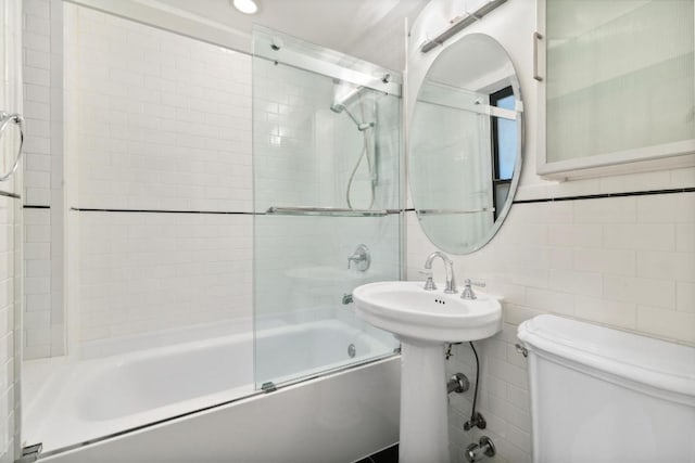 bathroom featuring toilet, tile walls, and shower / bath combination with glass door