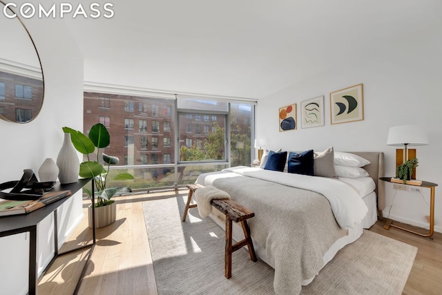 bedroom with floor to ceiling windows and light hardwood / wood-style floors