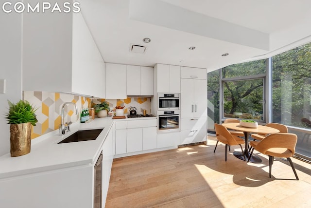 kitchen featuring sink, white cabinets, backsplash, and light hardwood / wood-style floors