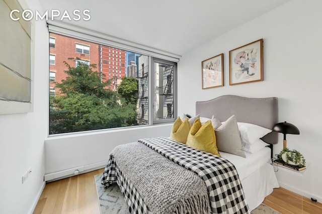 425 W 53rd St Unit 419, New York City, NY 10019 - bedroom with multiple windows, wood finished floors, baseboards, and a city view