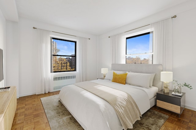 bedroom with radiator, parquet flooring, and multiple windows