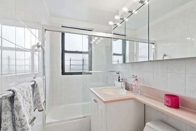 bathroom featuring decorative backsplash, tile walls, enclosed tub / shower combo, and vanity