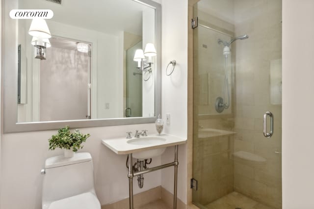 bathroom featuring sink, an enclosed shower, and toilet