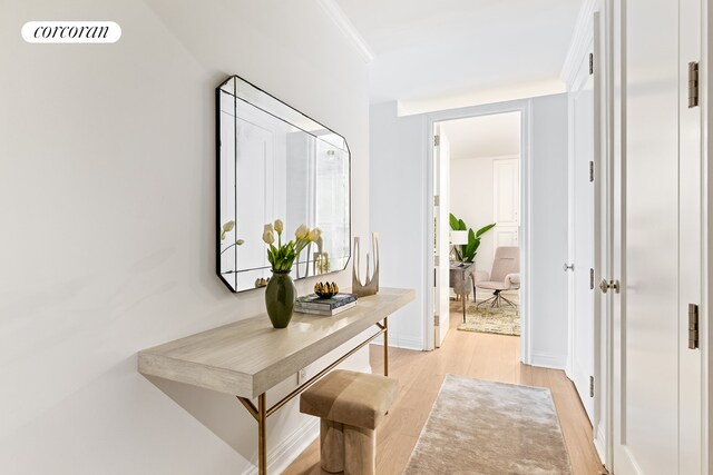 hallway featuring ornamental molding, light wood-type flooring, visible vents, and baseboards