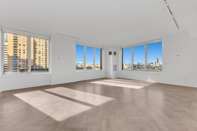 empty room with track lighting and parquet flooring