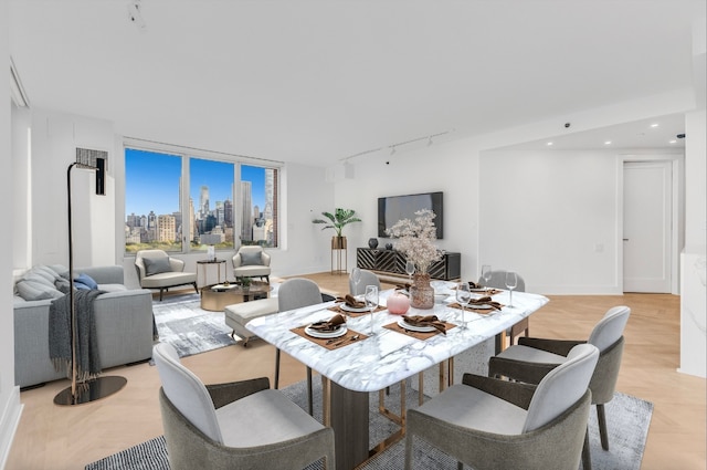 dining area featuring rail lighting and light parquet flooring