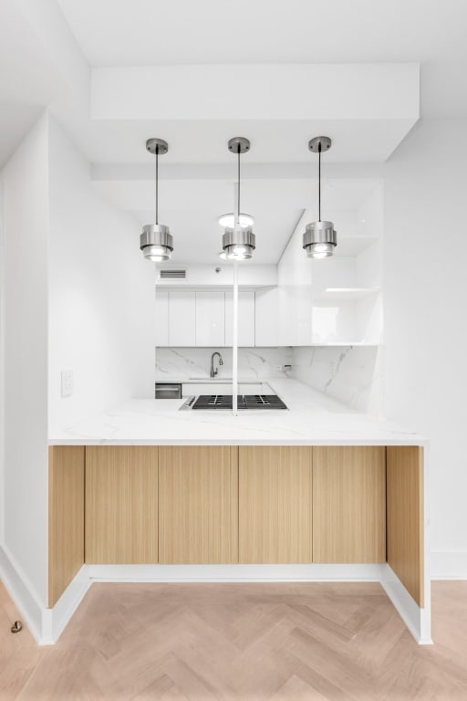 bar with white cabinetry, light stone counters, pendant lighting, stainless steel gas stovetop, and light parquet floors