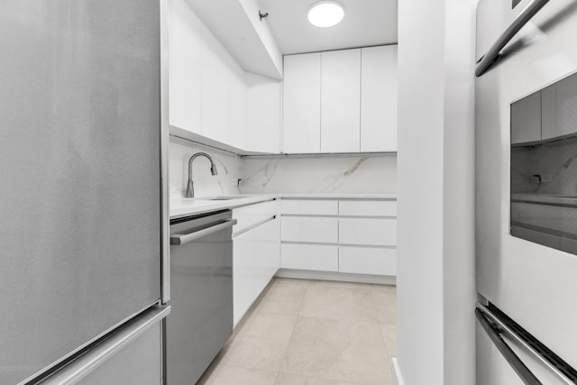 kitchen with white cabinetry, stainless steel appliances, sink, and decorative backsplash