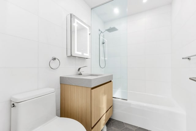 full bathroom featuring shower / bath combination, tile walls, vanity, tile patterned floors, and toilet