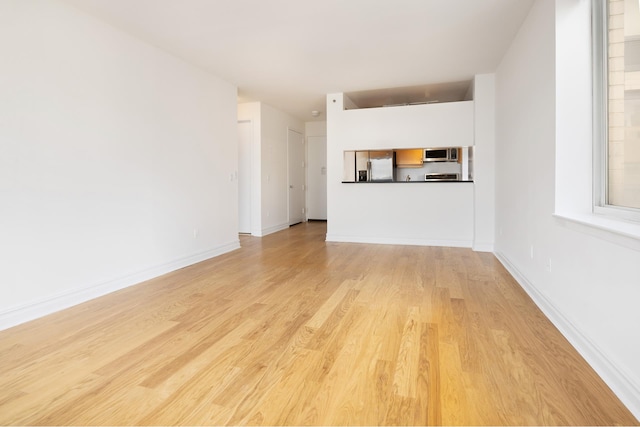 unfurnished living room with baseboards and light wood finished floors