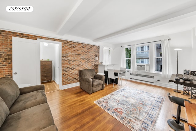 living room with radiator heating unit, cooling unit, brick wall, beam ceiling, and light hardwood / wood-style floors