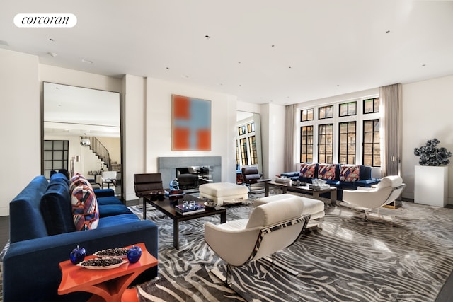 living area featuring stairs, a glass covered fireplace, and visible vents