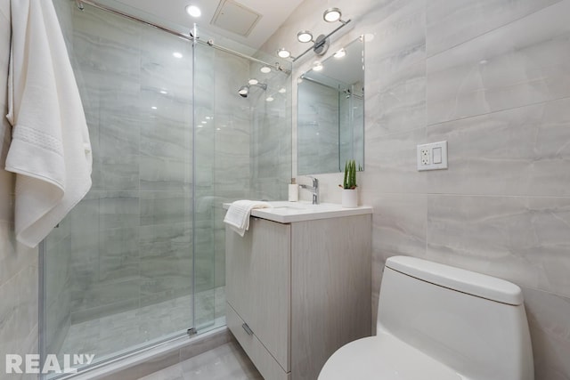 bathroom with vanity, toilet, and tile walls