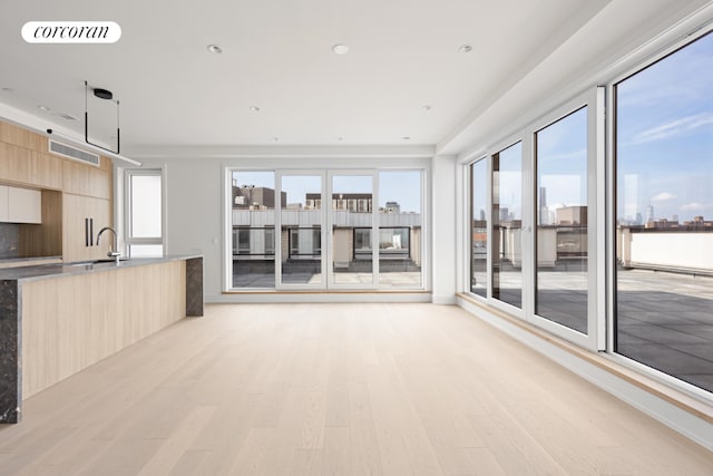 unfurnished living room featuring sink and light hardwood / wood-style flooring