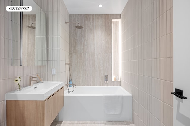 bathroom with tile walls, tiled shower / bath combo, vanity, and tasteful backsplash