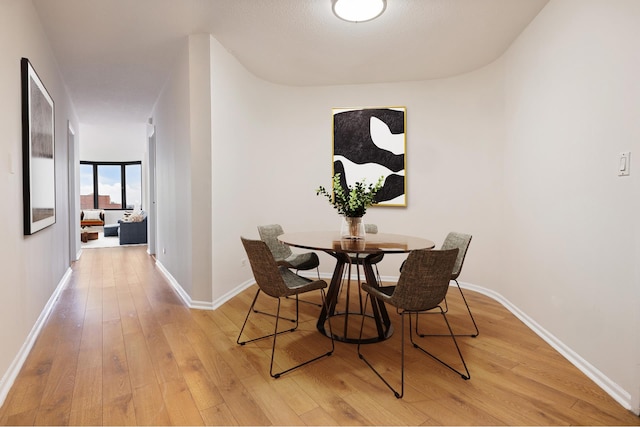 dining area with light wood-style flooring and baseboards