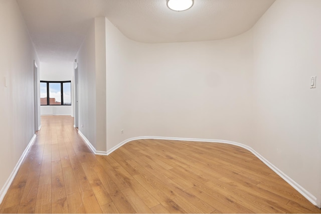 unfurnished room with baseboards and light wood-style floors