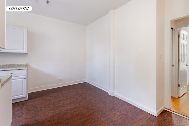 unfurnished dining area with dark wood-type flooring, visible vents, and baseboards