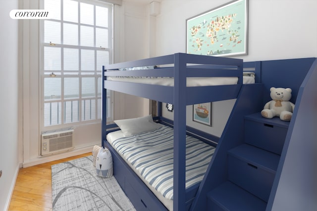 bedroom with a wall unit AC and wood finished floors