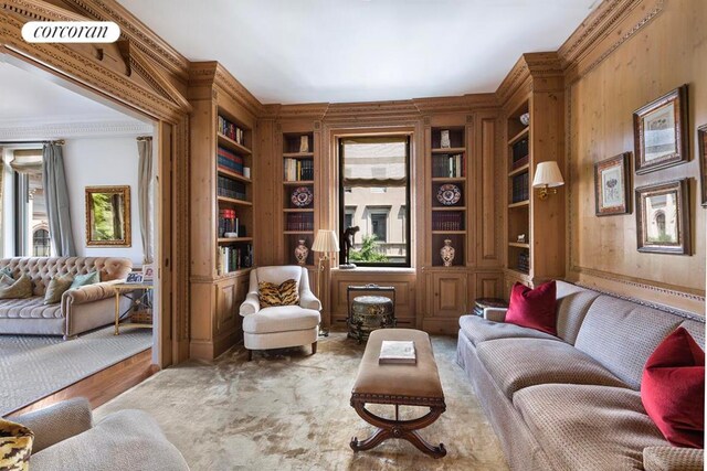 sitting room with light carpet, crown molding, wooden walls, and built in features