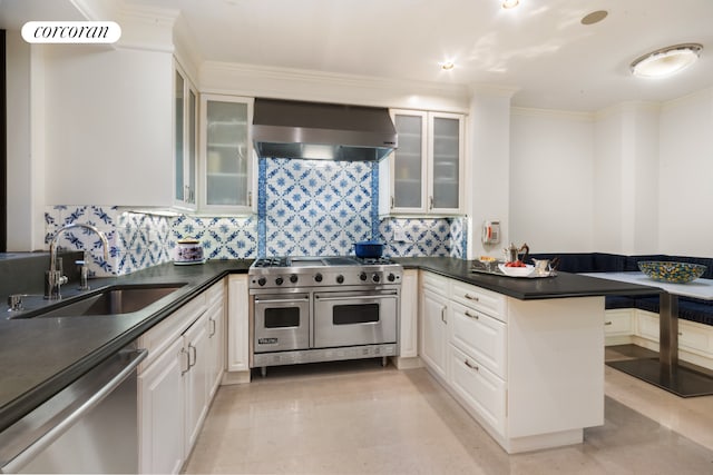 kitchen with a sink, dark countertops, stainless steel appliances, wall chimney exhaust hood, and a peninsula