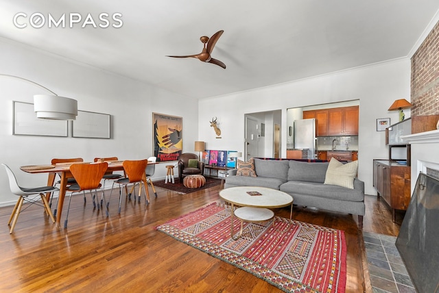 living room featuring dark wood-style floors, a large fireplace, and a ceiling fan