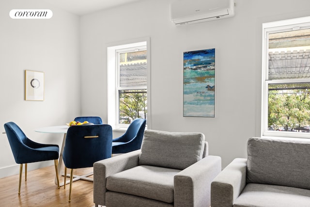 living area with an AC wall unit, wood finished floors, visible vents, and baseboards