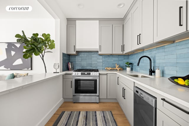 kitchen with visible vents, gray cabinetry, custom range hood, a sink, and stainless steel appliances