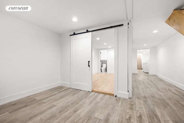 unfurnished room featuring light wood-type flooring, visible vents, a barn door, and recessed lighting