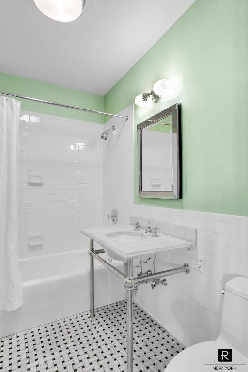 full bathroom featuring shower / tub combo with curtain, sink, tile walls, tile patterned flooring, and toilet