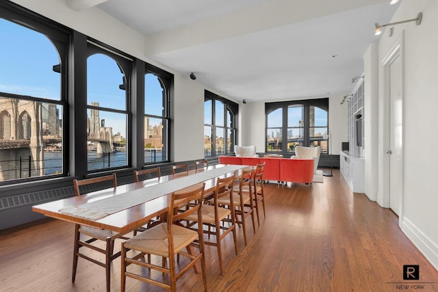 dining room featuring a city view, baseboards, and wood finished floors