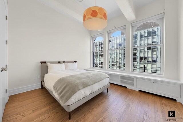 bedroom with hardwood / wood-style floors and beam ceiling