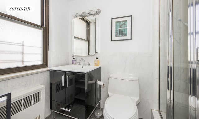 bathroom featuring toilet, vanity, tile walls, radiator, and a shower with door