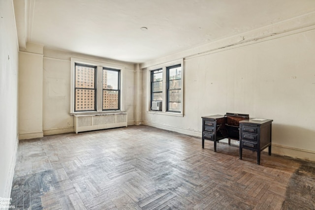 unfurnished room with parquet flooring, radiator, and a wood stove