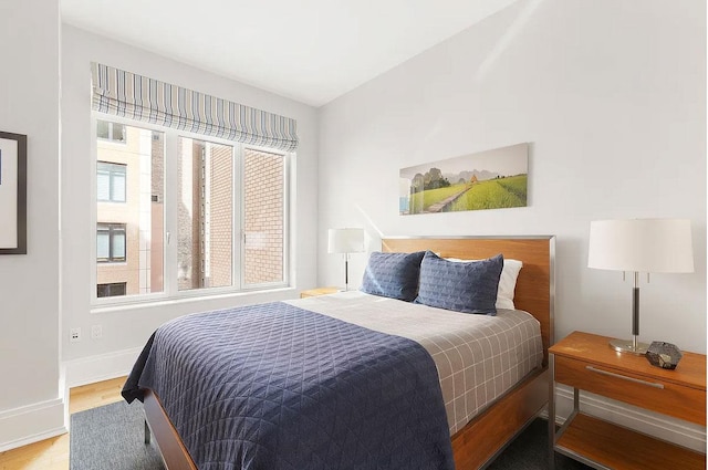 bedroom with baseboards, multiple windows, and wood finished floors