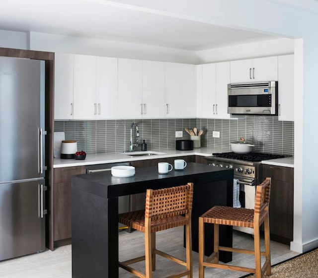 kitchen with high end appliances, a center island, sink, and tasteful backsplash