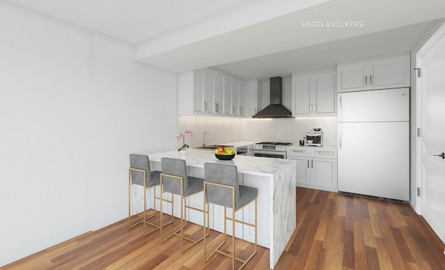 170 E End Ave Unit 2G, New York City, NY 10128 - kitchen featuring a peninsula, dark wood-type flooring, wall chimney exhaust hood, white cabinetry, and white fridge