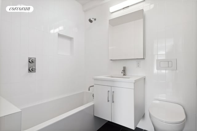 full bathroom featuring tile walls, vanity, tiled shower / bath, and toilet