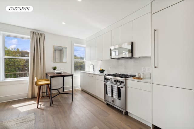 kitchen with visible vents, white cabinetry, stainless steel appliances, light wood-style floors, and light countertops