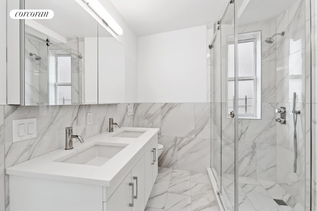 full bath featuring a marble finish shower, plenty of natural light, and a sink