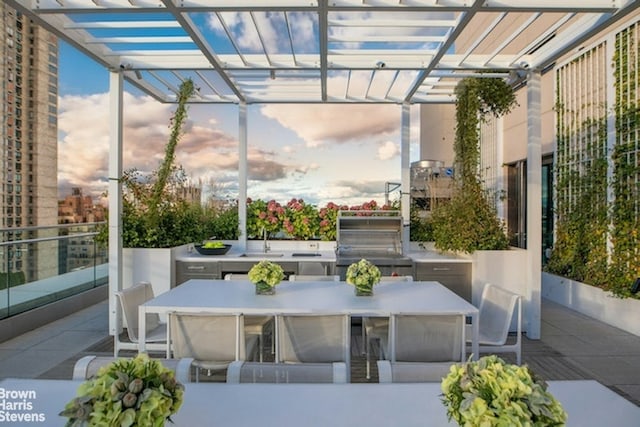 patio terrace at dusk with a pergola, area for grilling, and sink