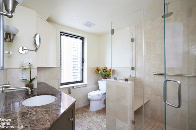 bathroom with toilet, a wealth of natural light, tile walls, and vanity