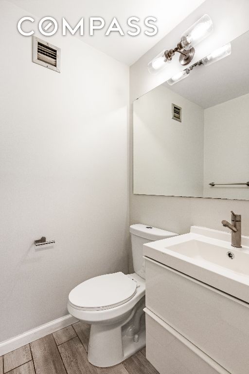 bathroom featuring vanity, wood-type flooring, and toilet