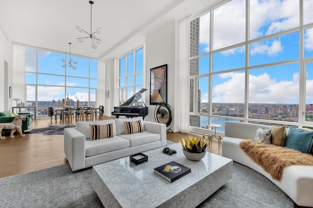 living room featuring expansive windows, a notable chandelier, a towering ceiling, and hardwood / wood-style flooring